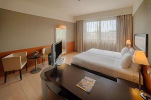 a hotel room with a large bed and a large window at NH Linate in Peschiera Borromeo