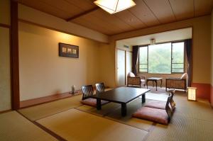 sala de estar con mesa, sillas y ventana en Jozankei Manseikaku Hotel Milione, en Jozankei