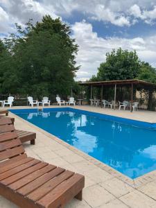 einen Pool mit weißen Stühlen und einem Pavillon in der Unterkunft Cabañas Bosques del Centro in Mina Clavero