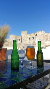 tres botellas y dos vasos en una mesa con un castillo en el fondo en High Flyers Kite House, en Tarifa