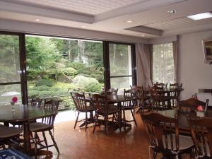 een eetkamer met tafels en stoelen en een groot raam bij Teiensaryo Yamanakako in Yamanakako