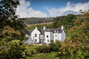 a large white house on a hill with trees at The Bellachroy Hotel in Dervaig