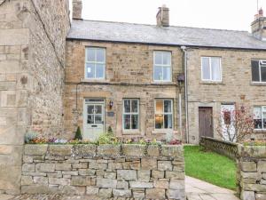 an old stone house with a stone wall at October Cottage in Barnard Castle