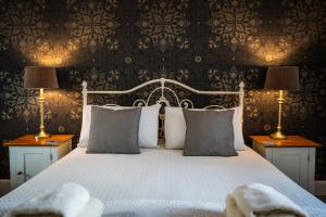 a bedroom with a white bed with two lamps at The Bellachroy Hotel in Dervaig