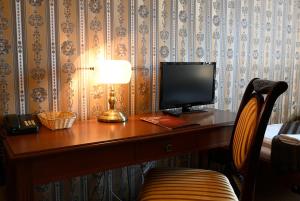 a wooden desk with a computer monitor and a lamp at Hotel Bouček in Kroměříž