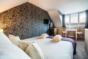 a hotel room with two beds and a table at The Bellachroy Hotel in Dervaig