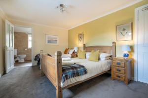a bedroom with a wooden bed with yellow walls at The Bellachroy Hotel in Dervaig