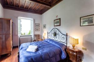 a bedroom with a blue bed and a window at Villa Serena & Dépendances in Cortona