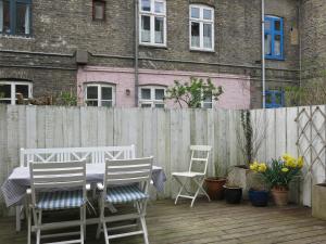 eine Terrasse mit einem Tisch, Stühlen und einem Zaun in der Unterkunft ApartmentInCopenhagen Apartment 1267 in Kopenhagen