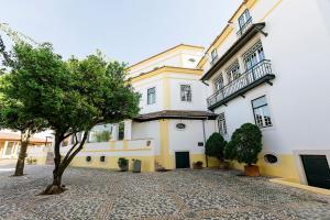 un grande edificio giallo e bianco con un albero di fronte di Hotel Lusitano a Golegã