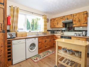 cocina con armarios de madera, lavadora y secadora en Rose Cottage, en Stoke Ferry