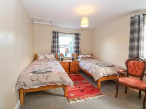 a bedroom with two beds and a chair and a window at Rose Cottage in Stoke Ferry