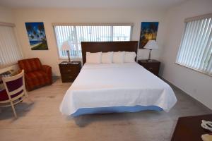 a bedroom with a large white bed and a chair at Surf Side Resort in Pompano Beach