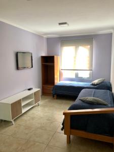 1 dormitorio con 2 camas y TV. en Polo Aparts en El Chaltén