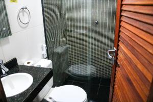 a bathroom with a shower and a toilet and a sink at Pousada Do Suiá in Arraial do Cabo