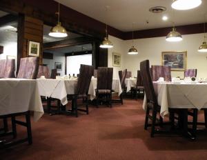 een eetkamer met witte tafels, stoelen en verlichting bij Motel à la Brunante in Sainte-Anne-des-Monts