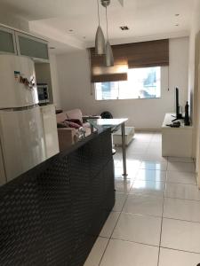 a kitchen with a refrigerator and a living room at Casa de Fábio in Porto Seguro