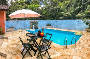 a table and chairs with an umbrella next to a pool at Pousada Maktüb in Peruíbe