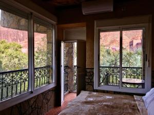 a bedroom with two windows and a bed with a view at La Petite Gorge, Hôtel & Restaurant Todra Gorge in Tinerhir