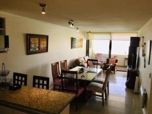 cocina y sala de estar con mesa y sillas en Departamento Jardín del Mar, en Coquimbo