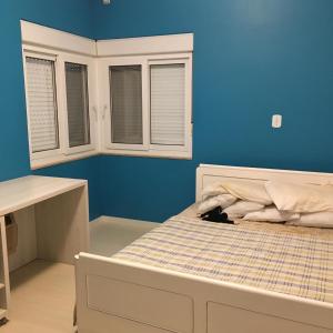 a bed in a room with a blue wall at Pousada Benedicto in Benedito Novo