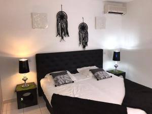1 dormitorio con cama blanca y negra con almohadas en TIBILIK en Saint-François