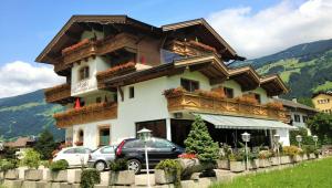 ein großes Gebäude mit davor geparkt in der Unterkunft Hotel Restaurant Rosengarten in Zell am Ziller