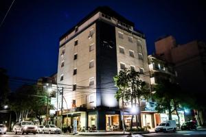 un grand bâtiment sur une rue de la ville la nuit dans l'établissement Hotel Ciudad, à Santiago del Estero