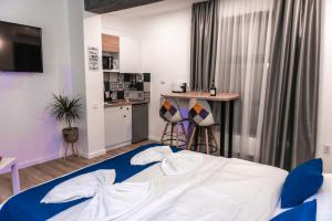 a bedroom with a blue and white bed and a kitchen at Puzzle Apartaments&Studios in Craiova