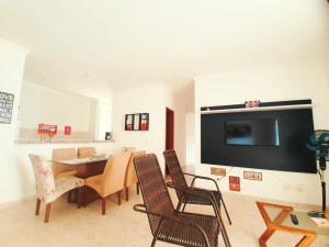 sala de estar con mesa, sillas y TV en Lindo apto com 3 quartos, apenas 1 quadra da praia das Toninhas, en Ubatuba