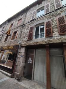 an old stone building with doors and windows at Chez Gustou in Chaudes-Aigues