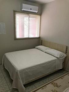 sypialnia z łóżkiem i oknem z klimatyzacją w obiekcie Apartamento foz centro 03 w Foz do Iguaçu