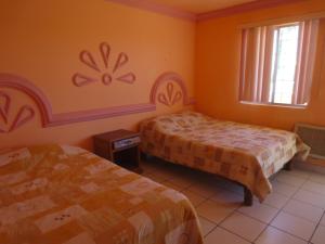 two beds in a room with orange walls at Hotel Plaza Peñasco in Puerto Peñasco