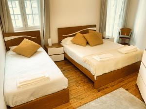una camera con 2 letti con lenzuola bianche e cuscini gialli di Guesthouse Tricana de Aveiro ad Aveiro
