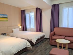 札幌市にあるドーミーイン札幌ANNEXのベッド2台とソファが備わるホテルルームです。