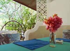 a vase of flowers on a table with a blue table cloth at Frangipani Cottages in Diani Beach