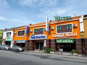 an orange hotel with cars parked in front of it at Lumut Hotel in Lumut