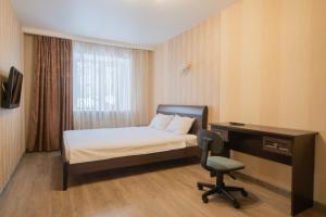 a bedroom with a bed and a desk and a chair at Apartments Petrovskie on Kirova 39A in Tomsk