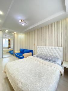 um quarto com uma cama branca e uma cadeira azul em Апартаменты Bliss в центре Казани em Kazan