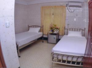 a room with two beds and a table with flowers at Hotel Shwe Eain Taw in Yangon
