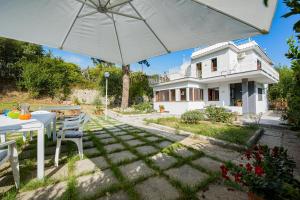 ein weißes Haus mit einem Tisch und einem Regenschirm in der Unterkunft Villa Louise Sorrento in Sorrent
