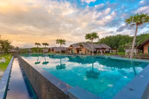 a large swimming pool with palm trees and houses at Venice Krabi Villa Resort in Ao Nam Mao