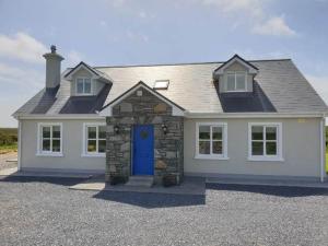 a large white house with a blue door at Hillside House in Ballinaboy