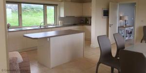 cocina con encimera, 2 sillas y mesa en Mannin Bay Beach House, en Ballyconneely