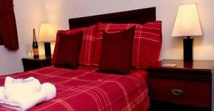 Un dormitorio con una cama roja con sábanas y almohadas rojas. en The Waverley Hotel en Crewe