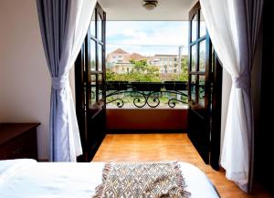 1 dormitorio con cama y vistas a un balcón en Le Petit Paris Dalat Hotel, en Da Lat