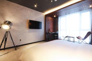 um quarto com uma cama, uma televisão e uma câmara em Hotel Laon em Busan
