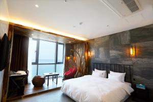 a bedroom with a large bed and a large window at Hotel Laon in Busan