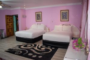 Duas camas num quarto com paredes cor-de-rosa em Lenasia Guest Lodge em Lenasia