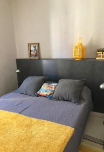 un lit avec une tête de lit noire et une couverture jaune dans l'établissement Le Machado, à Collioure